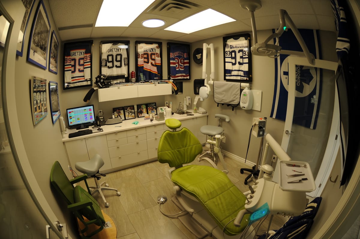 A treatment room at Cataraqui Woods Dentistry with framed hockey jerseys on the wall